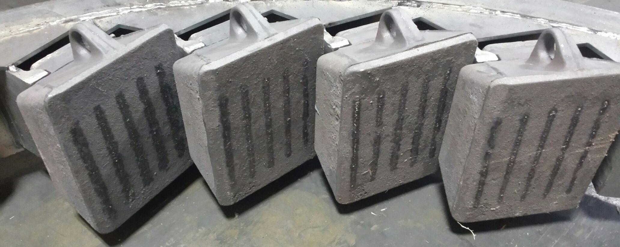 Four ceramic-reinforced anvil segments seated in a crusher anvil ring, reinforcement running down each wear face.