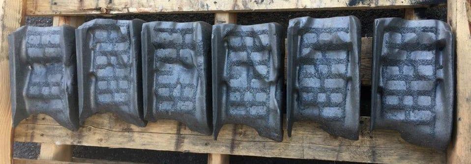 Six worn Si-Tec® ceramic shoes laid out on a pallet, wear faces up, the ceramic reinforcement showing through the worn surface.