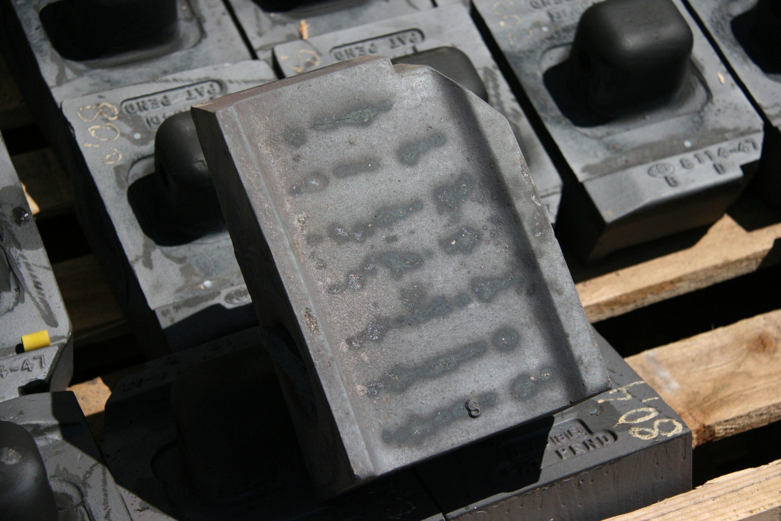 VSI wear shoes stacked on pallets, dark ceramic reinforcement banded across each wear face.