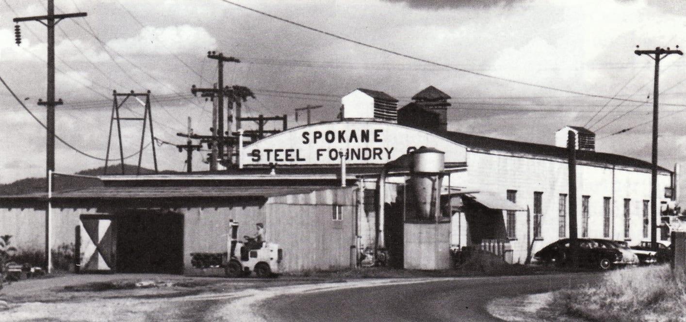 The Spokane Steel Foundry plant around 1960, its arched sign over the entrance and a forklift crossing the yard.